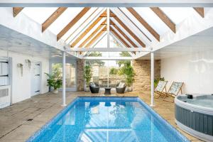 a swimming pool in a house with a ceiling at Historic country house retreat with indoor swimming pool and hot tub, ideal for large groups in Petty France
