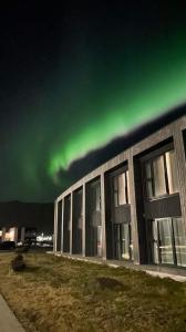 an office building with the green northern lights in the sky at Hótel Kría in Vík