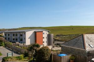 a view of a building with a hill in the background at Tregurrian Villas in Newquay