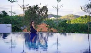 a woman sitting on the edge of a swimming pool at Ravishing Retreat Resort in Rāmanagaram