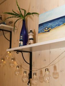 a shelf with lights and a painting on the wall at Sea Zone Domek całoroczny przy plaży in Dębki