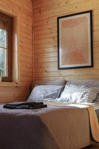 a bed in a wooden room with a picture on the wall at Sea Zone Domek całoroczny przy plaży in Dębki