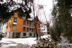 een oranje gebouw met sneeuw op de grond bij Luxury apartment Trio Harrachov A.2 in Harrachov