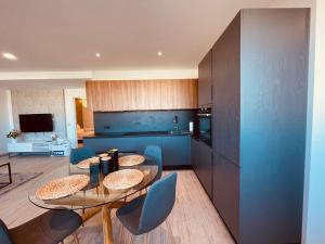 a kitchen with a glass table and blue cabinets at Ana Seafront Haven Apartment in Il-Gżira