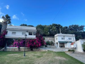 una casa blanca con flores púrpuras delante de ella en Villa Marver, en Algeciras