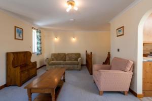 a living room with a couch and a table at Tregurrian Villas in Newquay