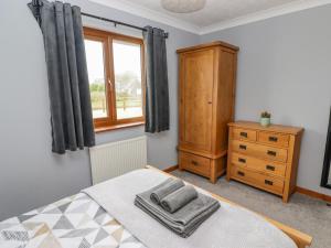 a bedroom with a bed and a dresser and a window at Ucheldir in Llanfyrnach