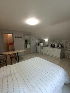ein großes Schlafzimmer mit einem weißen Bett und einer Küche in der Unterkunft studio 2 personnes entre campagne et plages in Questembert