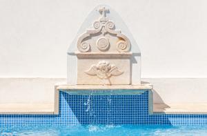 uma fonte numa piscina ao lado de uma piscina em Páteo dos Oliveira - Casa dos Senhores em Évora