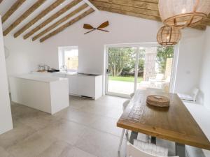 a kitchen with white cabinets and a wooden table at The Coach House in Amlwch