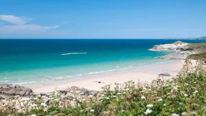 a beach with a group of people in the ocean at Tregurrian Villas in Newquay