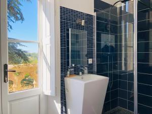 ein Bad mit einem Waschbecken und einer Dusche mit einem Fenster in der Unterkunft Château Fauchey in Cardan