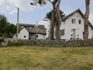 a white house with a stone wall and trees at The Coach House in Amlwch