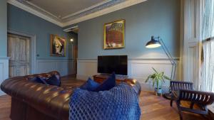 a living room with a leather couch and a television at Barbican Boutique Luxury Apartments & Rooms, Plymouth in Plymouth