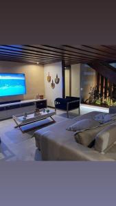 a large living room with a large television and a bed at Búzius na Praia da Ferradura Frente mar in Buzios