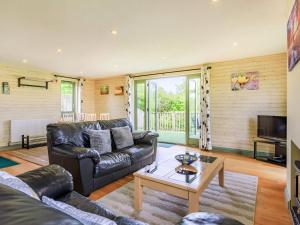 a living room with a leather couch and a coffee table at Primrose Lodge in Holsworthy