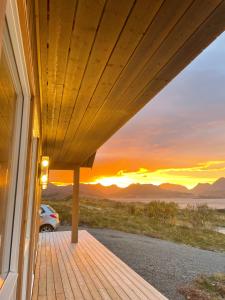 a house with a deck with the sunset in the background at Lofotenholidays, Luxury cabin with panoramic view in Leknes