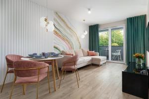 a living room with a couch and a table and chairs at Seaside Apartamenty 4 Pory Roku Kołobrzeg in Kołobrzeg