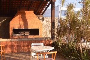 a patio with a brick fireplace with a table and chairs at Tuti Bororô in Rondonópolis