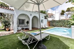 eine Terrasse mit einem Stuhl und einem Sonnenschirm neben einem Pool in der Unterkunft Casa en Sitges in Sitges
