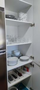 a white kitchen with plates and dishes on shelves at Acogedor apartamento con terraza en Portonovo in Portonovo