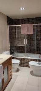 a bathroom with two sinks and a toilet and a tub at Acogedor apartamento con terraza en Portonovo in Portonovo