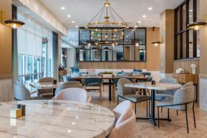 コロンビアにあるCambria Hotel Columbia Downtown the Vistaのテーブルと椅子、シャンデリアのあるレストラン