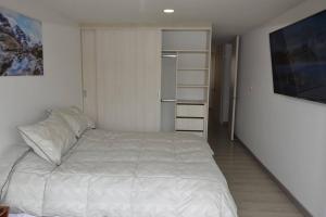 1 dormitorio con cama blanca y armario en Hermoso apartamento en Paipa con vista al lago Sochagota., en Paipa