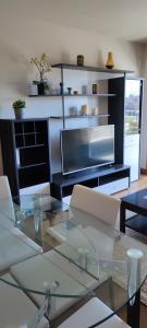 szklany stół z krzesłami i telewizor w salonie w obiekcie Acogedor apartamento con terraza en Portonovo w mieście Portonovo