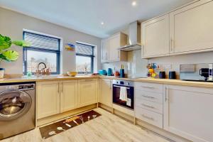 cocina con armarios blancos y lavadora en Chatham Serviced Apartments by Hosty Lets en Chatham