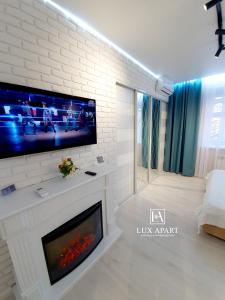 sala de estar con chimenea y TV en la pared en Lux апартаменты в центре Караганды на 45 квартале, en Karagandá