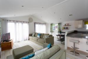 a living room with a couch and a kitchen at Spacious Homely Lakeside Lodge close to the Beaches in Chichester