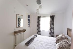 a bedroom with a white bed and a window at Spacious Homely Lakeside Lodge close to the Beaches in Chichester