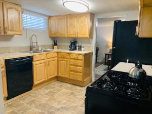 a kitchen with wooden cabinets and a black stove top oven at Inviting Bungalow Next to UNC - Free Cruiser Bikes in Greeley +37 photos