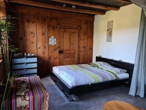 1 dormitorio con 1 cama y pared de madera en Ferme O'Clés en Le Peuchapatte