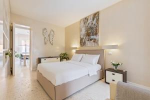 a bedroom with a large white bed and a chair at Petra Apartments in Rome