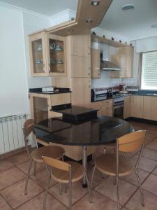 una cocina con mesa negra y sillas en A Morada de Julia, Acogedor apartamento en el balcón del Valle Miñor, en Pontevedra