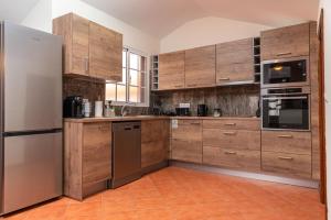 a kitchen with wooden cabinets and stainless steel appliances at CASA POR DO SOL in Calheta