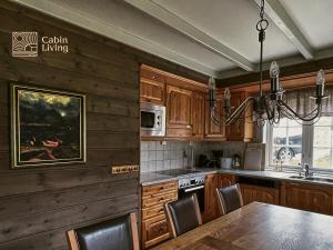 uma cozinha com armários de madeira, uma mesa e um lustre em Great apartment in Trysil, ski inout, wifi, sauna em Trysil
