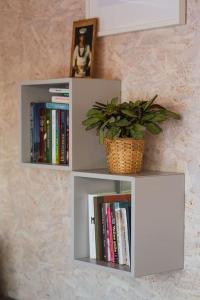 two white shelves on a wall with books at Beautiful Tiny house on the lake side. in Trakai
