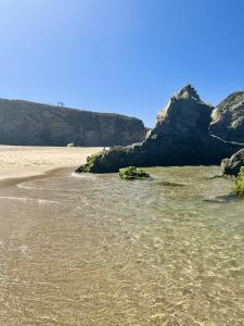 a beach with some rocks in the water at Apartamentos Guiomar Campos in Porto Covo