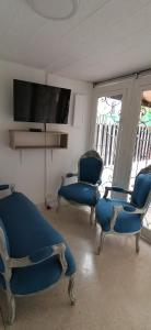 een wachtkamer met blauwe stoelen en een flatscreen-tv bij CASA HOTEL BOTERO in Medellín