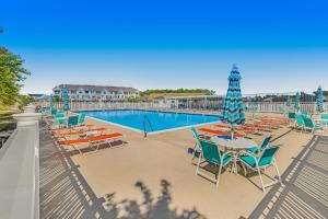 a pool with chairs and a table with a umbrella at Grande at Canal Pointe 37484 Liverpool Ln in Rehoboth Beach