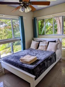 a bed in a bedroom with windows and a ceiling fan at Santuarios del Mar in Bocas del Toro