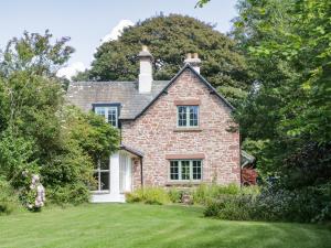 an old brick house with a grass yard at Caldhu Cottage in Holmrook