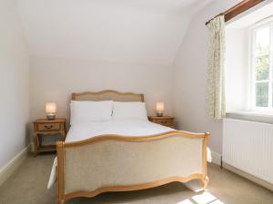 a bedroom with a bed with two night stands and two windows at Caldhu Cottage in Holmrook