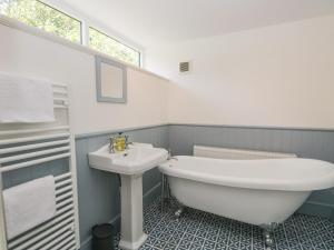a bathroom with a sink and a tub and a toilet at Caldhu Cottage in Holmrook