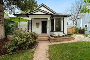 a small white house with a porch with an umbrella at Lola House! Cozy Comfort, Prime Old Town Location in Fort Collins