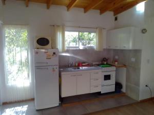 cocina con armarios blancos y nevera blanca en Las Moras en Villa Giardino