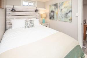 een slaapkamer met een wit bed en een houten hoofdeinde bij Cozy Retreat - Walk to UNC - Free Cruiser Bikes in Greeley